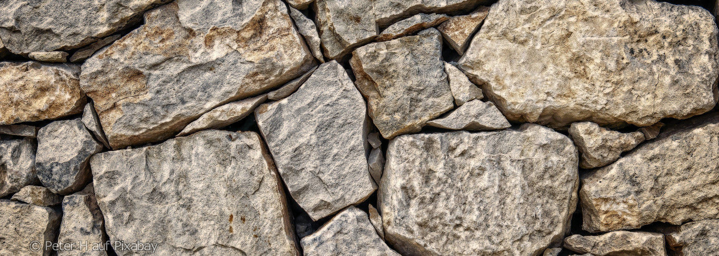 Nahaufnahme einer unregelmäßigen Mauer aus grob behauenen Natursteinen
