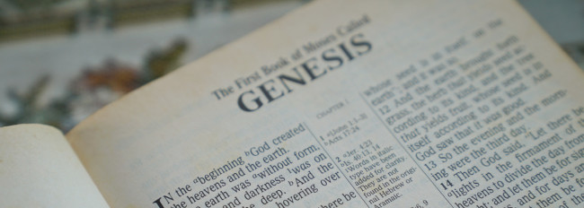 Aufgeschlagene Seite der Bibel mit dem Titel "Genesis" und dem Text des ersten Kapitels in englischer Sprache.
