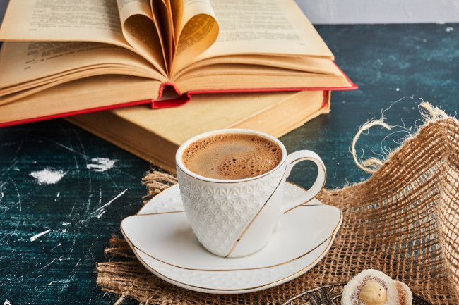 ein Kaffee mit einem Buch im Hintergrund